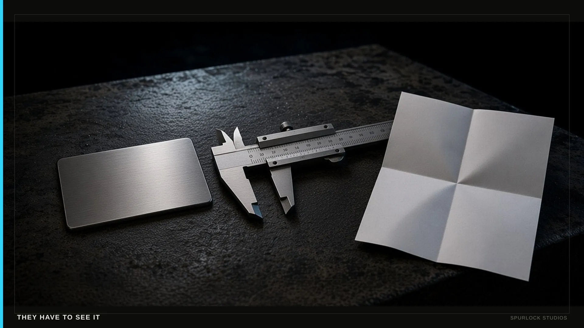 Metal sample coupon, spec sheet, and a caliper on black steel.